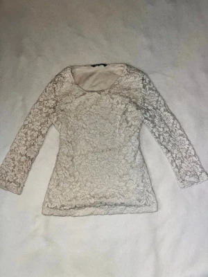 Vit spetsblus  - Säljer en vit spetsblus från H&M med blommigt mönster, lite kortare ärmar och blusen har rund halsringning.