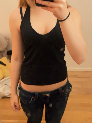 Svart croppad linnetopp - Snygg svart croppad linnetopp med smala axelband och djup v-ringning. Perfekt till jeans eller kjol för en enkel och stilren look. Skriv för mer info eller bilder! 🩷 pris är diskuterbart ⭐️