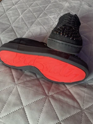 Christian Louboutins - Säljer Christian Louboutin med ikoniska röda sulor med  svarta nitar på tån. Skorna har snörning.