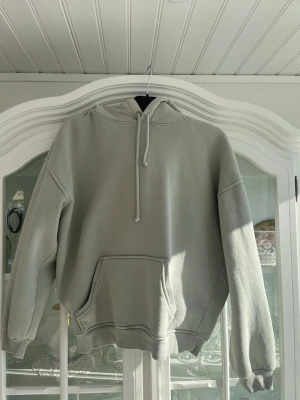 Ljusgrå hoodie från Bik Bok - Ljusgrågrön hoodie från Bik Bok i mjukt material med borstad insida. Klassisk modell med stor känguruficka framtill, ribbade muddar och justerbar dragsko i huvan. Perfekt för en avslappnad och chill stil.