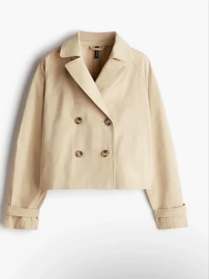 Kort beige trenchcoat från H&M - Stilren kort trenchcoat i beige från H&M med dubbelknäppning framtill och klassisk krage. 