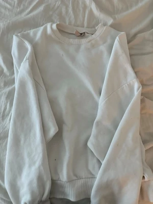 Vit oversized sweatshirt - En enkel och stilren vit sweatshirt i oversized modell. Tröjan har rund halsringning, långa ärmar och ribbade muddar vid ärmslut och nederkant. Perfekt för en avslappnad och trendig look. Materialet känns mjukt och bekvämt mot huden.