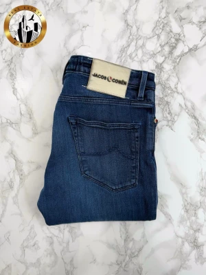 Jacob Cohën 32 - Mörkblå Jacob Cohën Style 696 jeans i storlek W32 i mycket bra skick. Byxorna har inga lagningar men det förekommer mindre slitningar i utkanten på bälteslappen, se bild 4. Tveka inte på att höra av dig för fler bilder eller vid minsta fundering! Självklart äkta. Skick: 8/10 | Mått A: 43cm | Mått B: 89cm | Mått C: 70cm 