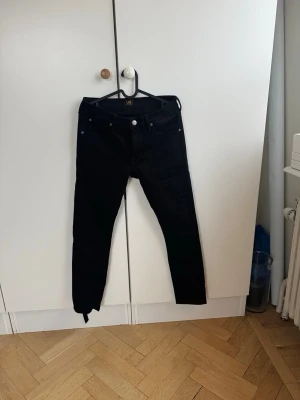 Svarta skinny jeans från Lee - Säljer ett par svarta skinny jeans från Lee med klassisk femficksdesign och dragkedjegylf. Jeansen har en smal passform och är tillverkade i stretchigt material för extra komfort. Perfekta för dig som gillar en clean och stilren look. Storleken ser ni på bild. Aldrig använda nypris 1000 kr 