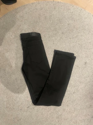 Svarta raka jeans från vero Moda  - Säljer ett par svarta jeans från vero Moda med rak passform och klass safety five-pocket design. Jeansen har diskreta sömmar och är tillverkade i ett mjukt denim as material som känns bekvämt hela dagen. Perfekta för en clean och stilren look.