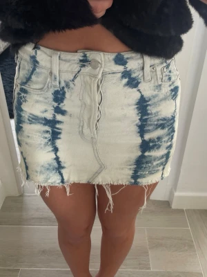 Jeans kjol - Säljer en kort jeanskjol i blått och vitt med tie-dye mönster. Kjolen har råa, fransiga kanter och klassiska fickor fram och bak. Storlek Xs men passar mig som oftast har M i nederdelar.