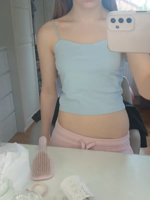 Ljusblå ribbad linnetopp - Säljer en ljusblå linnetopp med smala axelband och croppad passform. Toppen är ribbad och har en enkel, stilren design som passar perfekt till jeans eller kjol. Superenkel att styla och riktigt skön på sommaren.