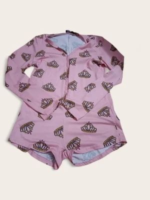 Rosa pyjamas med kronmönster - Söt rosa pyjamas Tryckt med gulliga kronor i gult och rosa samt texten 'Princess' på ryggen. Mjuk och stretchig bomullsblandning som känns skön mot huden. Perfekt för mysiga hemmakvällar.