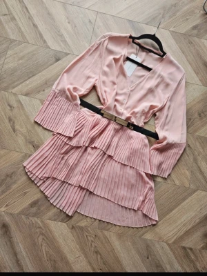 Mesh Ljusrosa Zara plisserad kortklänning - Populär slutsåld Supersöt ljusrosa kortklänning med plisserade volanger och vida ärmar. Klänningen har v-ringning, knappar framtill och är tillverkad i ett lätt, flowy material. Perfekt för dig som gillar en feminin och trendig stil. Såååå fin❤️1 o 2 bild lånad