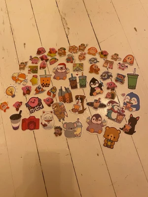 Söta klistermärken med djurmotiv - Ett set med färgglada klistermärken som föreställer gulliga djur, drycker och tecknade figurer. Motiven inkluderar pingviner, björnar, katter, boba tea och kameror. Perfekt för att dekorera dator, mobil eller anteckningsbok.