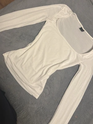 Vit långärmad topp Gina Tricot - Säljer en enkel och stilren vit långärmad topp från Gina Tricot. Toppen har en rundad, något djupare ringning och är tillverkad i ett mjukt och stretchigt material som sitter tight mot kroppen.  Köpt för kanske 250kr
