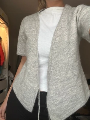 Ljusgrå omlottkofta - Säljer en ljusgrå omlottkofta med korta ärmar och knytband i midjan.  Använd fåtal ggr 