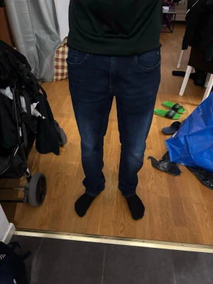 Mörkblå raka jeans herr - Säljer ett par mörk initialt tvättade jeans i rak modell för herr. Jeansen har klass ahead femficksdesign, normal midja och är tillverkade i denim med lätt stretch för extra komfort. Perfekta för en avslappnad och stilren look.