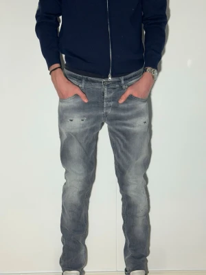 Grå dondup jeans med schyssta slitningar skinny fit - Säljer ett par grå jeans med smal passform och slitna detaljer framtill. Jeansen har klassisk femficksmodell och dragkedjegylf. Perfekta för en avslappnad och trendig look.