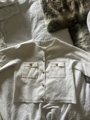 Vit cardigan med guldknappar - Stilren vit cardigan med guldknappar från H&M