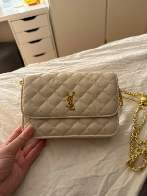 Vit väska  - Väskan har magnetlås och elegant rutmönster. Perfekt för dig som vill ha en lyxig och stilren accessoar.