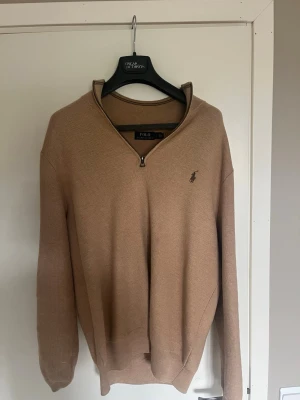 Beige tröja från Polo Ralph Lauren - Beige tröja från Polo Ralph Lauren med halv dragkedja och diskret broderad logga på bröstet. Bra skick, säljer pga att den inte passar längre!