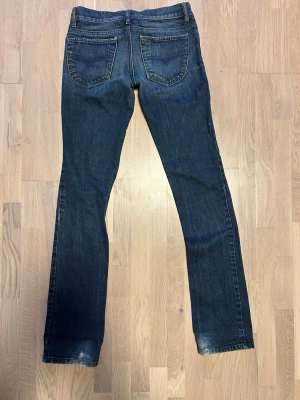 Mörkblå bootcut jeans från Diesel - Snygga mörkblå bootcut jeans från Diesel med klassisk femficksmodell och slitningar framtill. Jeansen har låg midja och raka ben, perfekta för en avslappnad och trendig look. 