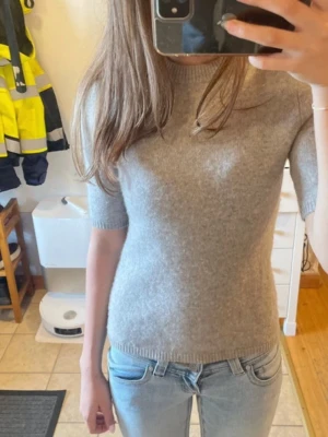 Stickad t-shirt! - Mysig grå stickad topp med korta ärmar och rund hals. Sitter fig- pikant och har ribbade kan som ger en clean look. Perfekt till jeans eller kjol för en enkel men snygg stil.