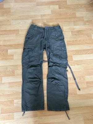 Mörkgröna cargobyxor med snören - cargopants khaki storlek 31 men går att göra mindre pga spännband i midjan