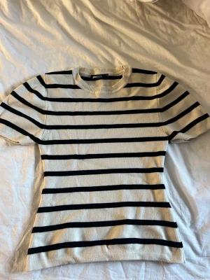 Randig topp från Gina Tricot - Säljer en vit och svart randig topp från Gina Tricot. Toppen har rund halsringning, korta ärmar och är i ett mjukt, ribbat material. Inte använd mycket alls! Säljer pågrund av att den blivit för liten!