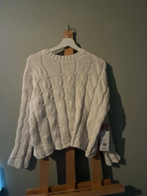 Vit kabelstickad tröja Samsa - Säljer en vit kabelstickad tröja från Samsa Collection i storlek M. Tröjan har ett chunky mönster, rund halsringning och långa ärmar. Priset går att prata om. Helt oanvänd och köpt på Ullared. Perfekt för dig som gillar en klassisk och mysig look till hösten eller vintern.