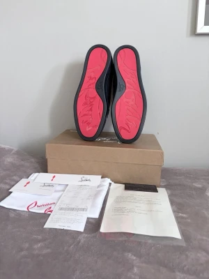 Mörkblå sneakers från Christian Louboutin - Snygga mörkblå sneakers i mocka från Christian Louboutin med klassisk röd sula och diskret logga på sidan. Perfekta för dig som vill ha en exklusiv och stilren look. Hör av er vid minsta fundering! Mvh Quadra Closet!