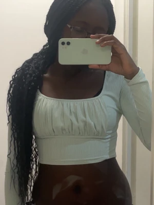 Ljusgrön croppad långärmad topp - Trendig ljusgrön croppad topp med långa ärmar och fyrkantig ringning. Toppen har ribbad struktur och lätt rynkade detaljer framtill för en snygg look. Perfekt att matcha med höga jeans eller kjol.