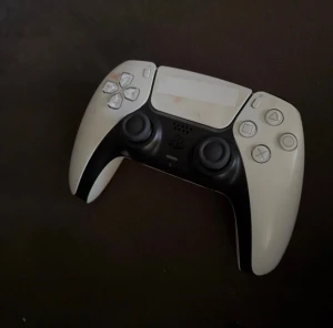 DualSense handkontroller till PS5 - 6 DualSense handkontroller till PlayStation 5. En i klassisk vit och svart design och en i helvit. Båda har touchpad, inbyggd mikrofon och ikoniska PlayStation-knappar. Ergonomisk form och tillverkade i plast med matt finish.