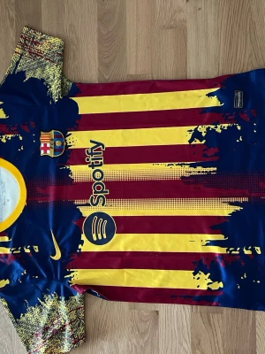 Barcelona matchtröja gul/röd Nike - Säljer en FC Barcelona matchtröja från Nike med coolt grafiskt mönster i gult, rött och marinblått. Tröjan har klubbmärke, sponsorlogga och korta ärmar med unikt mönster. Perfekt för fotboll eller som statement-plagg.