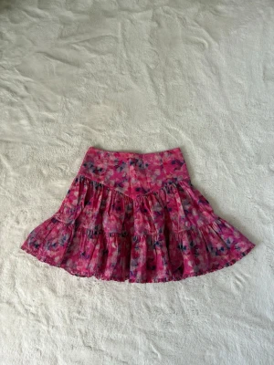 Rosa blommig kort volangkjol ifrån Costommade - Jättefin rosa mönstrad kort kjol ifrån märket custommade i storlek xs/s som är i mycket bra skick, bara använd nån gång och perfekt till sommaren🌸 Tex till studenter och midsommar. Den är unik, har en fin passform och är färgglad. Kjolen är i bra material, sval och skön. Skriv om funderingar, lämna gärna ett omdöme och priset kan diskuteras😊