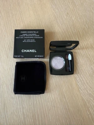 Chanel Ombre Essentielle 251 Gris Rose - Lyxig ögonskugga från Chanel i nyansen 251 Gris Rose, en metallisk ljusrosa färg. Kommer i en elegant svart dosa med spegel och applikator samt tillhörande sammetsfodral och originalkartong. Perfekt för att skapa en sofistikerad look. Helt oanvänt.