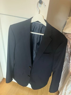 Klassisk svart kavaj med två knappar och kostymbyxor  - Snygg svart kavaj med två knappar framtill och klassisk passform, med kostymbyxor. 