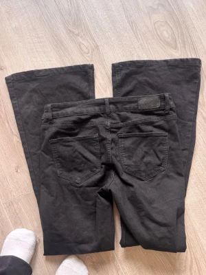 Svarta bootcut jeans - Säljer ett par svarta bootcut jeans. Jeansen har klassiska fem fickor, hällor för bälte och en snygg utsvängd passform. Materialet är mjukt och stretchigt, perfekt för dig som gillar en bekväm och trendig look.