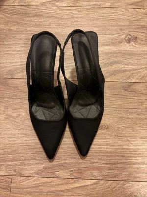 Svarta spetsiga slingback-pumps - Svarta Klackskor Säljer dessa snygga svarta klackskor. Perfekta för alla tillfällen, från fest till vardag. Bekväma och stilrena. Säljes i nyskick! Aldrig använda, bara testade. Skyddsplast kvar.