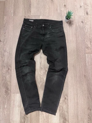 Svarta jeans från Levis  - Säljer ett par svarta jeans från Levis 502 med klassisk femficksmodell och raka ben. Jeansen har en lätt tvättad look och är tillverkade i denim. Perfekta för dig som gillar en avslappnad och stilren vibe.