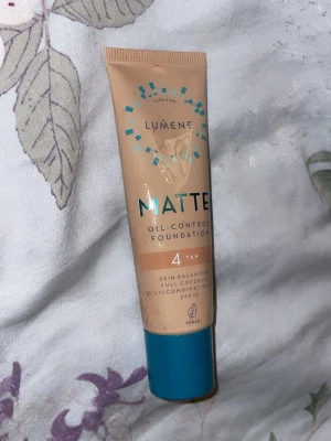 Lumene Matte Foundation 4 Tan - Matt foundation från Lumene i nyansen 4 Tan. Ger oljekontroll och full täckning, perfekt för blandhy. Tuben är beige med blått lock och har SPF20. Vegansk formula.