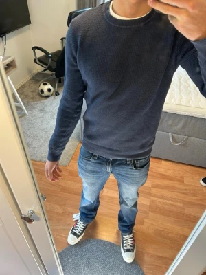 Mörkblå stickad tröja  - Säljer en mörkblå stickad tröja . Tröjan har rund halsringning, långa ärmar och ribbade muddar vid ärmslut och nederkant. Perfekt till jeans eller chinos för en clean och stilren look.