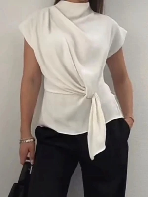 Vit omlottopp med knyt i midjan - Stilren vit topp med omlottdesign och knyt i midjan. Toppen har hög hals, är ärmlös och har en elegant, lös passform. Perfekt för dig som gillar minimalistisk och modern stil. Hade ett lite håll på ryggen men har fixat och sytt det! 💕
