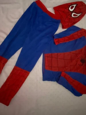 Spiderman dräkt maskeradset - Säljer ett Spiderman maskeradset med blåa byxor, röd-blå tröja med spindeltryck och tillhörande mask. Dräkten har klassiska Spiderman-färger och nätmönster. Perfekt för cosplay eller maskerad. Materialet är mjukt och stretchigt tyg.   159kr/ paket 