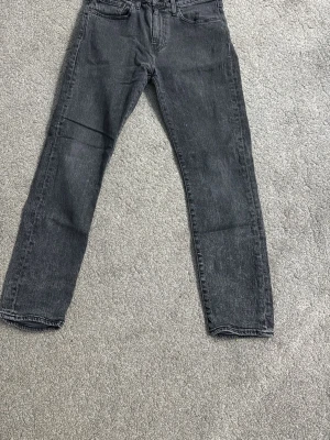 Grå raka jeans från Levi's storlek W31 L30 - Säljer ett par grå jeans från Levi's storlek w31 L30 med rak passform och klassisk femficksdesign. Jeansen har en diskret tvättad look och är tillverkade i slitstark denim. Perfekta för en avslappnad och trendig stil.