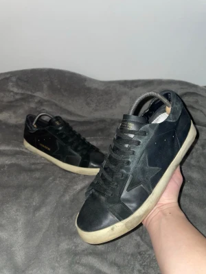 Golden Goose ⭐️ - Ett par snygga Golden Goose ⭐️ i färgen svart. Dem är helt okej skick eftersom dem är bara lite smutsiga och dem är storleken 42 samt är de slitna vid bakdelen av uppsidan. Jag gick till en skomakare och han fixade sulan av skorna för dem va lite slitna och efter det så har dem hållit bra och det är vattentätt! (Kolla sista 3 bilderna) 
