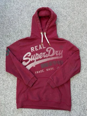 Vinröd hoodie från Superdry - Säljer denna RIKTIGT FETA superdry tröjan, mycket bra skick 9,5/10. Storlek S (passar även M) Det är bara att skriva vid några frågor, kan vara om prisförslag eller hur storleken passar!