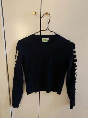 Mörkblå stickad tröja From Future - Mörkblå stickad tröja från From Future med rund hals och långa ärmar. Tröjan har vita grafiska detaljer längs båda ärmarna (står hypnotize) Perfekt för dig som gillar en enkel men ändå cool look. Materialet känns mjukt och bekvämt. Storlek xs/xxs