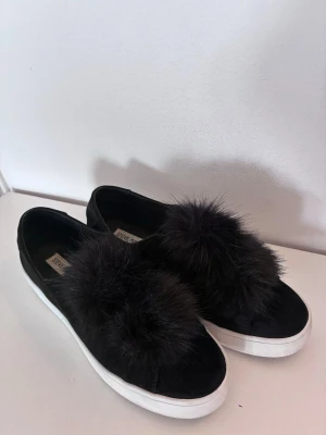 Svarta loafers med päls Steve Madden - Svarta loafers från Steve Madden med fluffiga pälsdetaljer på ovansidan och vit sula. Skorna har en slip-on design och är tillverkade i mockaliknande material. Perfekta för dig som vill sticka ut med en unik och trendig look. Använda fåtal gånger. Storleken passar snarare en 39.
