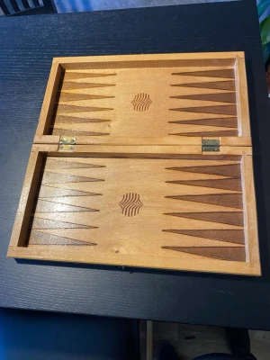 TRÄ sckack Träschack och backgammon bräde brädspel  - Säljer ett kombinerat spelbräde i trä för schack och backgammon. Brädet har ett klassiskt rutmönster på utsidan för schack och inuti finns backgammonmönster med dekorativt snidade detaljer. Perfekt för spelkvällar med vänner eller familj.