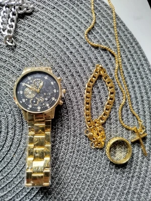 Guldfärgad klocka från Soki - Stilren guldfärgad klocka från Soki med metallarmband och svart urtavla med detaljerad design. Klockan har en rund form och markerade siffror runt urtavlan. Perfekt accessoar för dig som vill sticka ut.ligger ute igen pga oseriös köpare 400kr, Postnord 