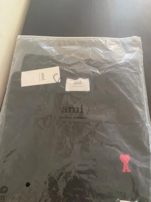 Svart t-shirt från Ami Paris - Snygg svart t-shirt från Ami Paris med klassisk passform. T-shirten har ett rött hjärta med bokstaven A broderat på bröstet och rund halsringning. Tillverkad i mjuk bomull och perfekt för en clean och stilren look.