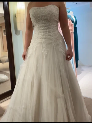 Brudklänning - Jättefin oanvänd brudklänning i syl 38. Klänningen har en klassisk, romantisk look med markerad midja och fint släp. Känns inte tung när du har den på dig. Perfekt för dig som vill ha en drömmig och stilren klänning. Nypris 12000:-