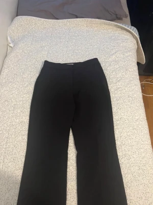 Svarta kostymbyxor från H&M - Snygga svarta kostymbyxor från H&M i klassisk rak modell. Byxorna har hög midja och stängs med knapp och dragkedja. Perfekta till en stilren look och passar till många olika outfits.